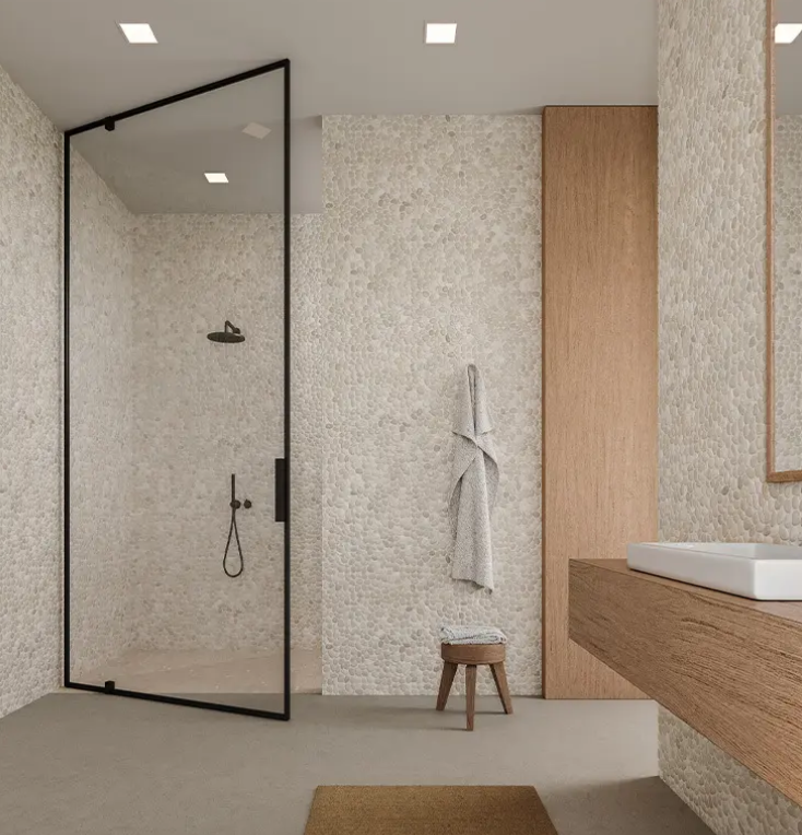 Image features  a bathroom complete with walls covered in 12x12 Natural Stone Mosaic Tile in Tan from Urban Coast Tiles Pebble Collection
